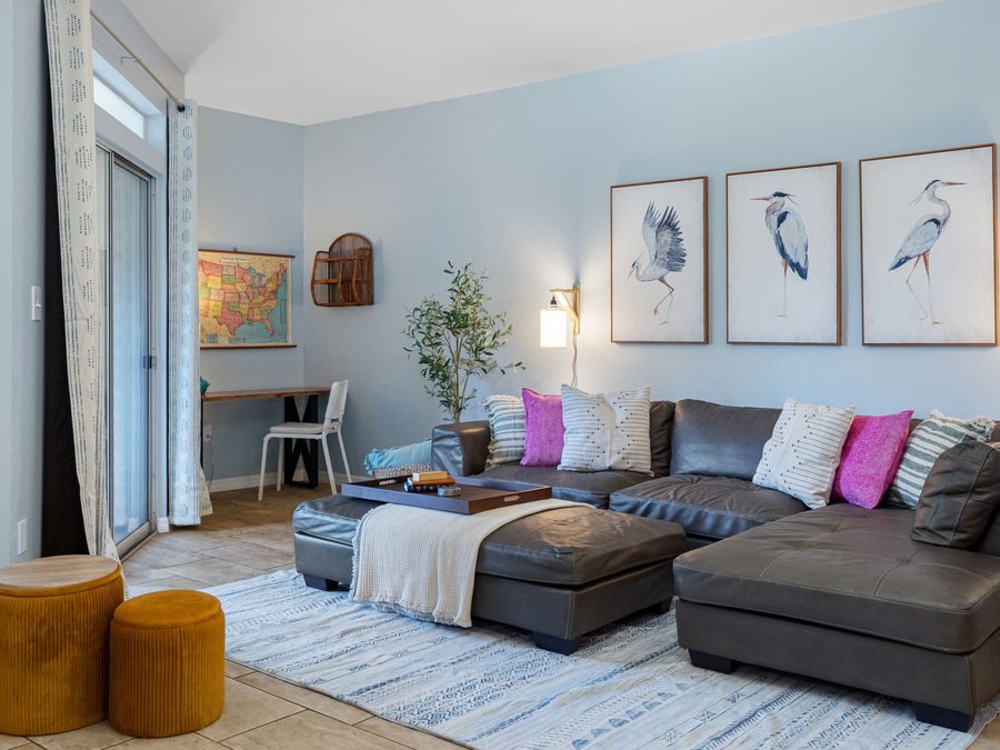 Condo living room with heron prints, a sectional and mustard poufs