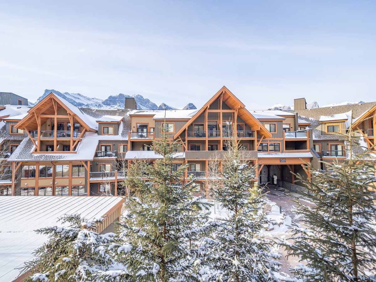 Snow-covered mountain lodge buildings in Canmore, Alberta with peaks behind