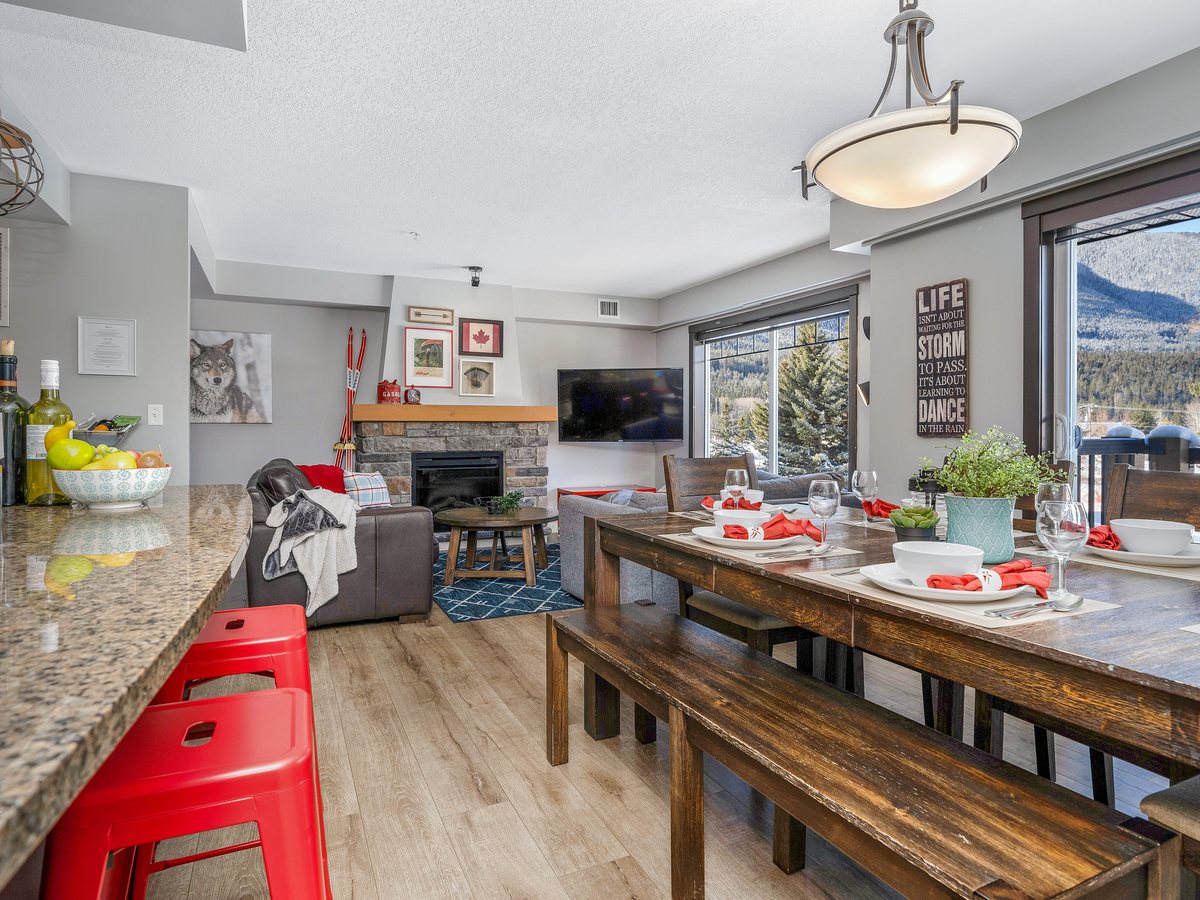 Open-plan mountain condo with a stone fireplace, red bar stools and a long dining table set for eight