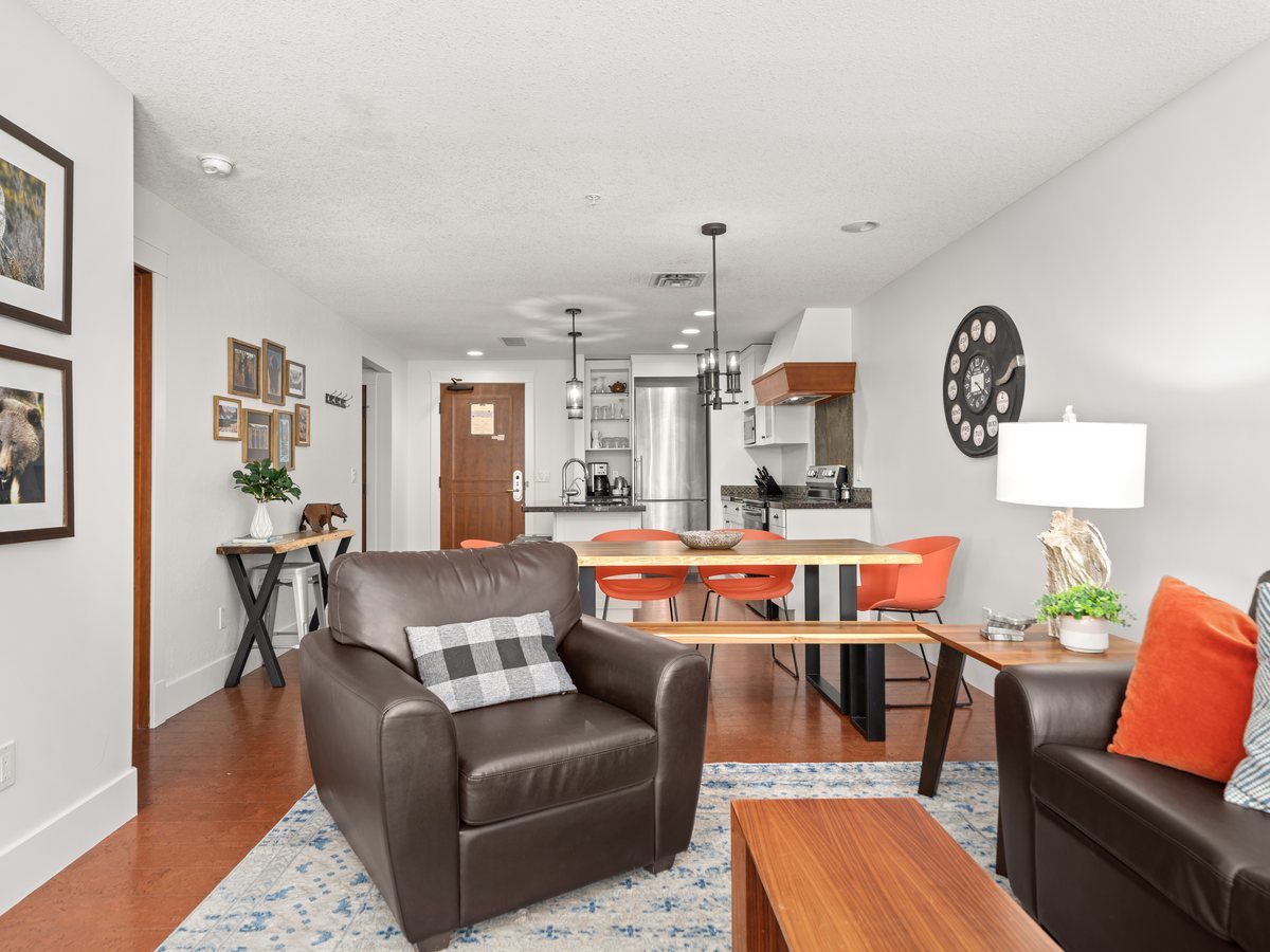 Mountain condo living room with orange dining chairs, a live-edge table and framed wildlife photography