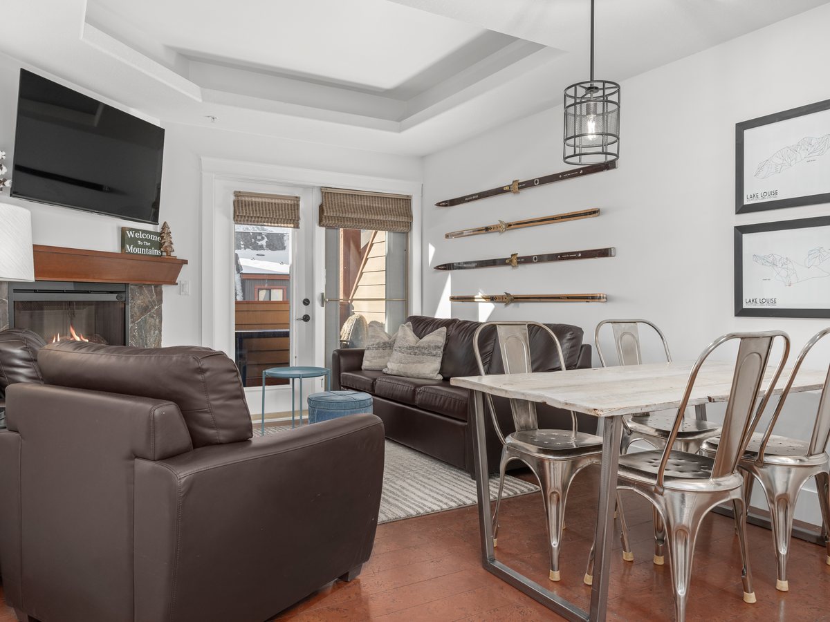 Mountain living room with a gas fireplace, vintage skis mounted on the wall and framed ski-hill prints