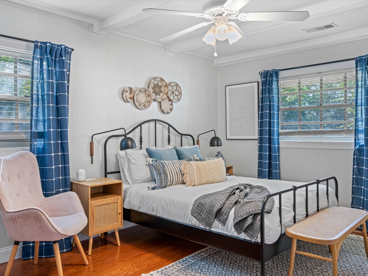 Bedroom with indigo curtains, woven wall baskets and a blush velvet armchair