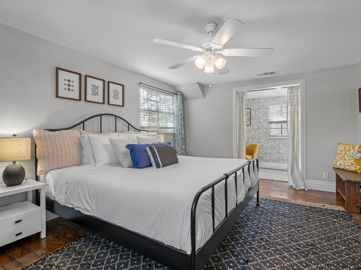 Bedroom with a black iron bed, framed geometric prints and a navy woven rug