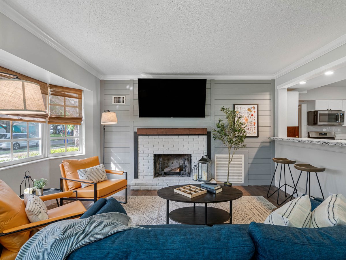 Living room with orange leather chairs, a blue sofa and a shiplap fireplace wall