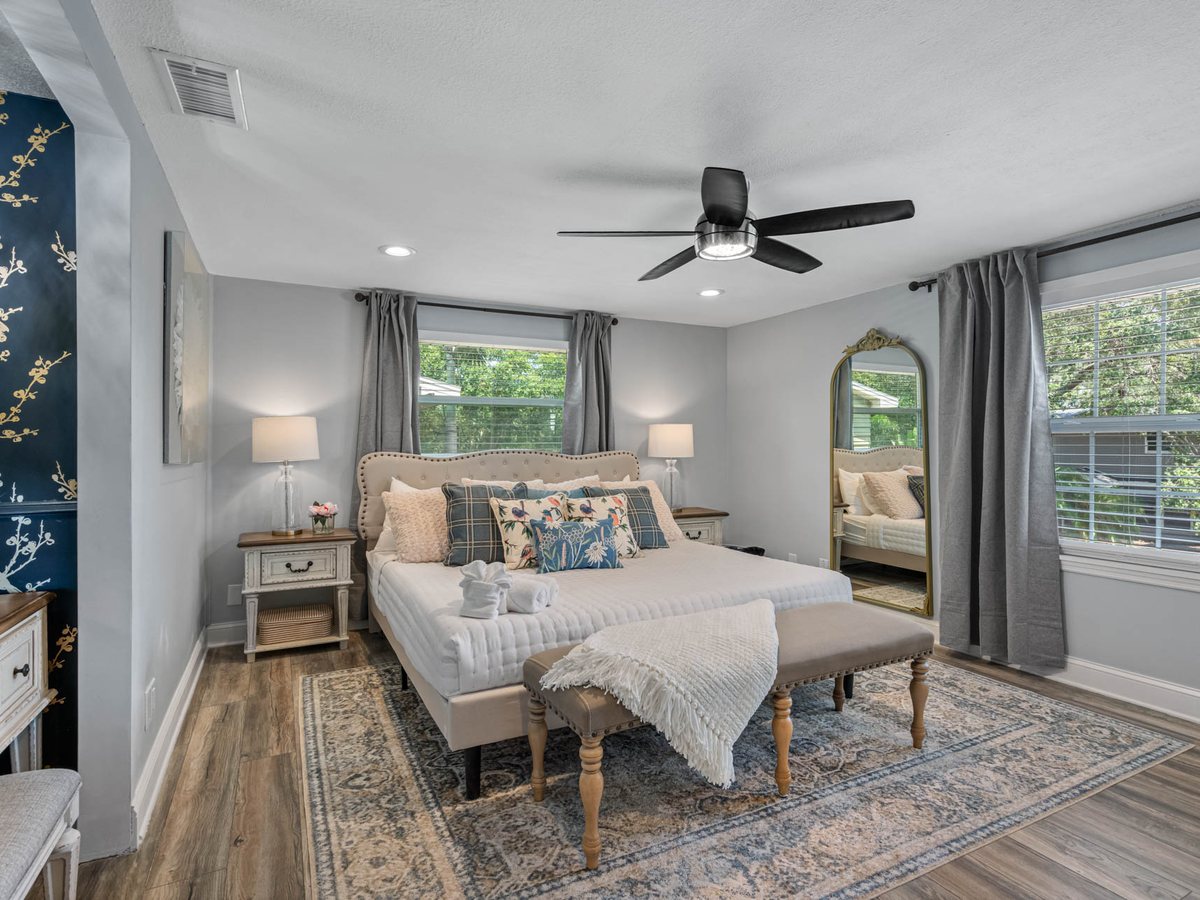 Primary bedroom with a chinoiserie feature wall, upholstered bed and a gold-framed floor mirror